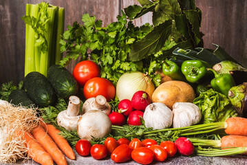 Still life based on vegetables such as celery, leeks, tomatoes, peppers, carrots, mushrooms, aubergines, potatoes, onions, garlic, cucumber, and radishes, vegetarian background.