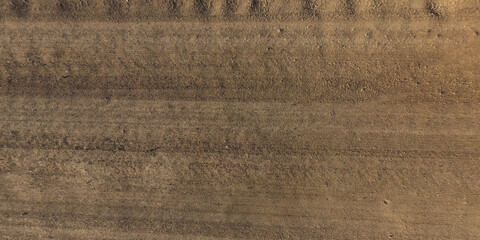 panorama of surface from above of gravel road with car tire tracks
