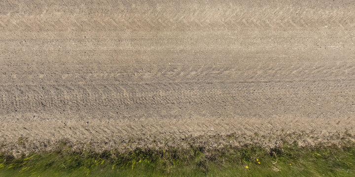 Panorama Of Surface From Above Of Gravel Road With Car Tire Tracks With Roadside And Grass