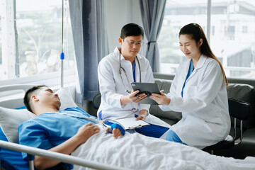 Obraz premium Two doctors talking to a patient lying in his bed with receiving saline solution in hospital .