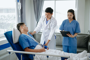 Two doctors talking to a patient lying in his bed  with receiving saline solution in hospital .