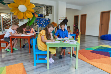Creative kids during an art class in a daycare center or elementary school classroom drawing with...