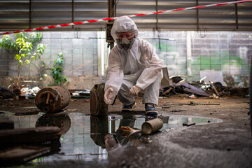Worker wearing safety uniform and gas mask they used stretching the red white warning tap in...