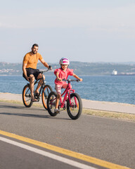 Fototapeta na wymiar Father and daughter with bike on the coast