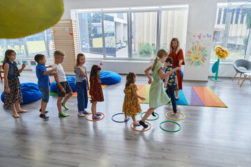 Small nursery school children with female teacher on floor indoors in classroom, doing exercise....