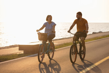 Couple taking pleasure in the ride on beach cruiser bikes, pedaling on a wonderful route near the...