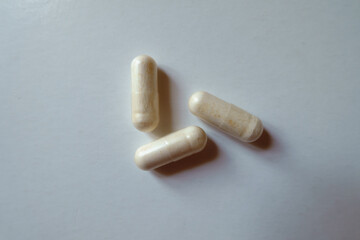 Three light beige capsules of probiotic dietary supplement from above