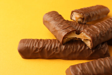 Sweet tasty chocolate bars with caramel on yellow background, closeup