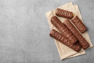 Sweet tasty chocolate bars with caramel on grey table, top view. Space for text