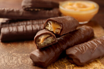 Sweet tasty chocolate bars with caramel on wooden table, closeup