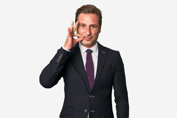 A middle-aged businessman isolated with fingers on lips keeping a secret.