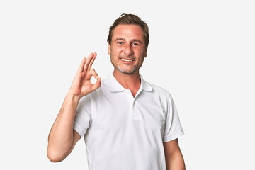 A middle-aged man isolated cheerful and confident showing ok gesture.