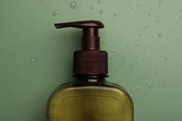 Bottle of face cleansing product on green background, top view