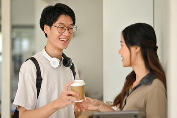 Smiling young college friends talking while standing at lockers in campus. Youth lifestyle concept