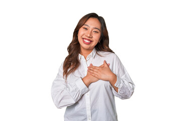 A young chinese woman has friendly expression, pressing palm to chest. Love concept.