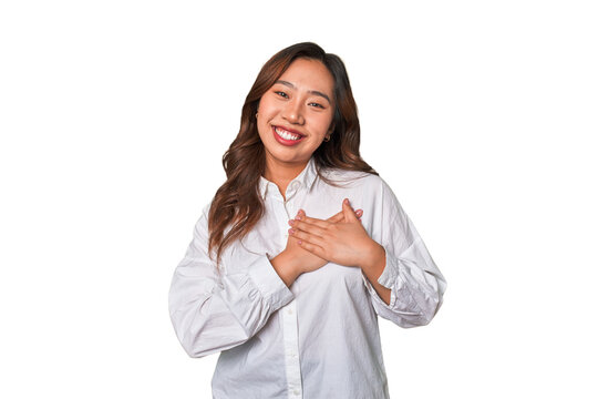 A young chinese woman has friendly expression, pressing palm to chest. Love concept.