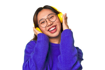 Joyful Asian woman wearing headphones, enjoying music and having fun