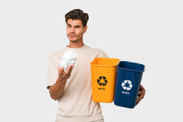 Young caucasian man holding recycling bins isolated on white background