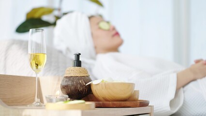 Close up spa equipment with woman laying on spa bed feeling relaxed with cucumber slices on eyes in blured background. Spa aromatherapy concept