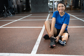 Fototapeta na wymiar Happy Asia woman with prosthetic leg exercise at gym or fitness 