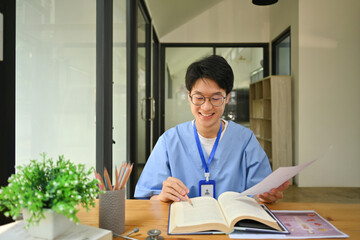 Medical student reading books, preparing for university exams in library. Medical internship concept