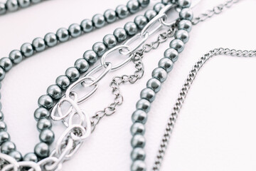 A necklace of gray beads with chain decorations on a white aesthetic background.