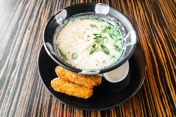 Thai soup Tom Kha Gai in a plate with fish close-up.
