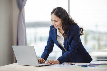 happy young woman excited at work Successful Asian businesswoman with laptop smartphone at work.