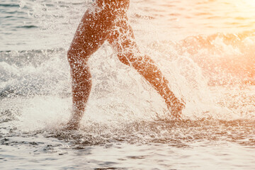 Running woman on a summer beach. A woman jogging on the beach at sunrise, with the soft light of the morning sun illuminating the sand and sea, evoking a sense of renewal, energy and health.