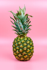 Whole ripe pineapple on the pink background