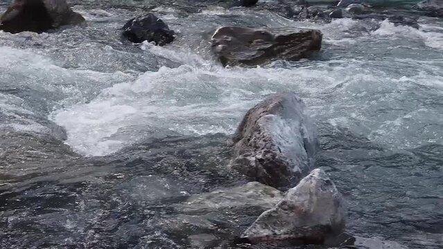 Kander river: shallow Glacier white meltwater rapids flowing through rocky creek. in swiss alps of Kandertal, switzerland.