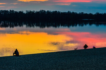 Fototapeta na wymiar Fishermen at the bank of the river at sunset. Silhouette photo