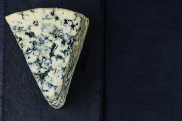Piece of the blue cheese with mold on slate board. Top view