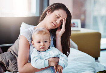 Fototapeta na wymiar Stress, headache and a a mother with her baby in a bedroom of their home together in the morning. Children, family and burnout with a tired mama sitting on a bed with an infant son as a single parent