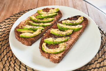 Tempting avocado toast on wooden table.