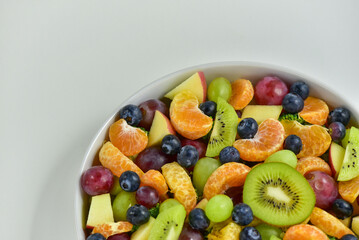 Healthy fresh fruit salad bowl on white background. Top view. Healthy food concept, healthy high vitamin fruit, mixed fruit background.