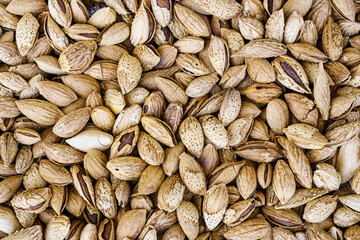 The texture of a heap of almonds in a shell. Background of healthy plant vegan food. Nuts.