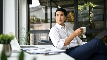 Successful Asian businessman thinking and planning his business while having coffee