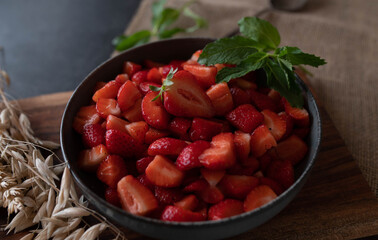 Bowl with marinated and chopped strawberries on rustic background
