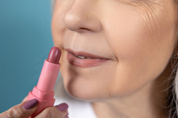 Beautiful aging woman with lipstick doing makeup