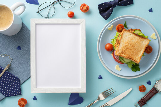 Surprise Dad with a special breakfast on Father's Day. Top view of a homemade sandwich, coffee cup, napkin, necktie, and other men's accessories on pastel blue background with an empty frame for text
