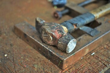 Old hammer with a wooden handle wrapped with electrical tape on the master's desktop.
