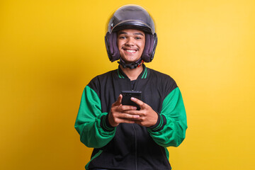 Asian online taxi driver motorbike wearing green jacket and helmet while holding smartphone...