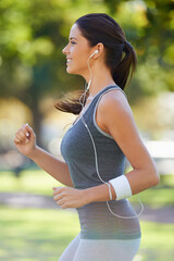 Sports, earphones and athlete running in a park for health, wellness and outdoor exercise. Nature, fitness and female runner doing cardio workout in garden listening to music or radio and training.