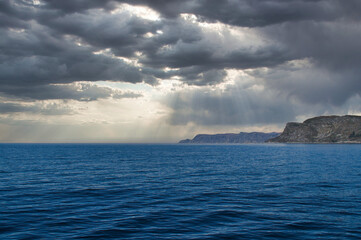 View from the sea to the West Cape in Norway in sunshine with heavy clouds.