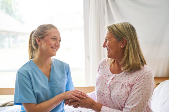 Nurse holding hand of senior woman at rehab center