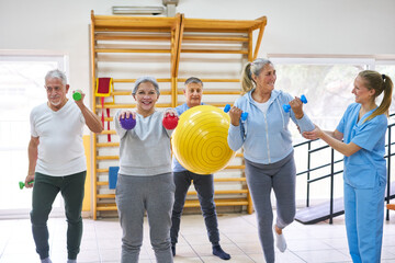 Therapists assisting elderly people exercising at fitness class