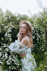Beautiful, stylish, cute blonde in a white dress with a green pattern as a model for a photo shoot...
