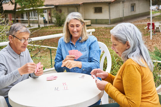 Senior friends playing cards in garden of nursing home