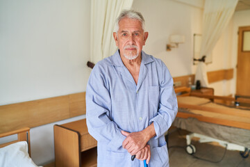 Fototapeta premium Elderly man with walking cane standing in nursing home